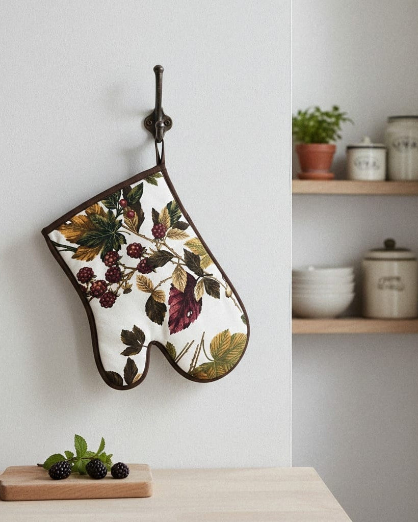Floral-patterned oven mitt hanging on a wall with a shelf in the background