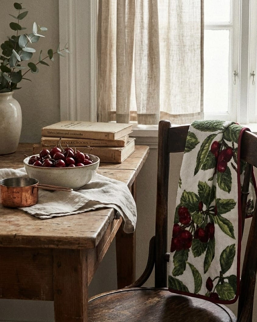 Dining room with wooden table, chair, and books near a window.