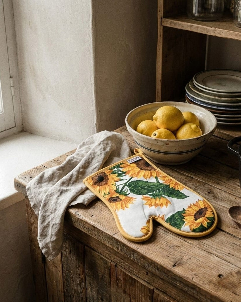 Kitchen counter with sunflower-themed pot holder, bowl of lemons, and stack of plates.
