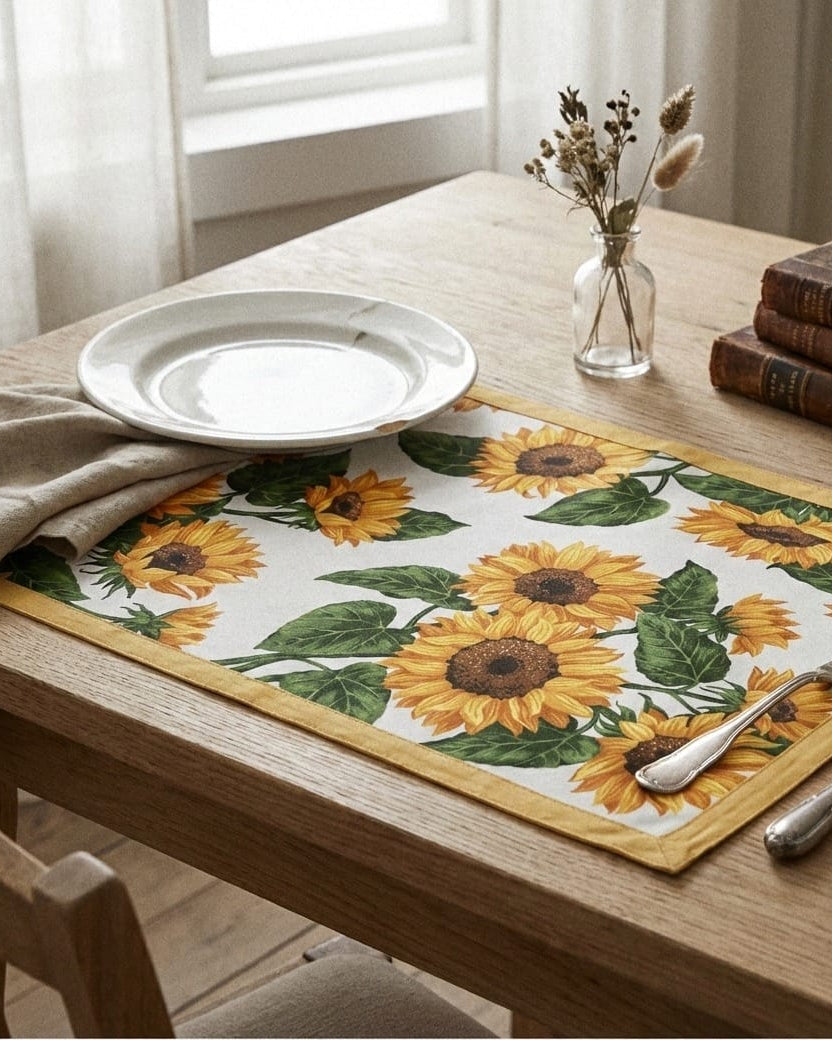 Dining table with sunflower placemat, white plate, and cutlery.