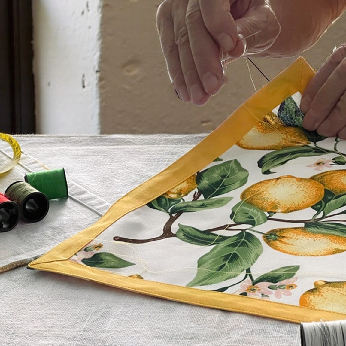 Person measuring a fabric with a floral pattern on a table.
