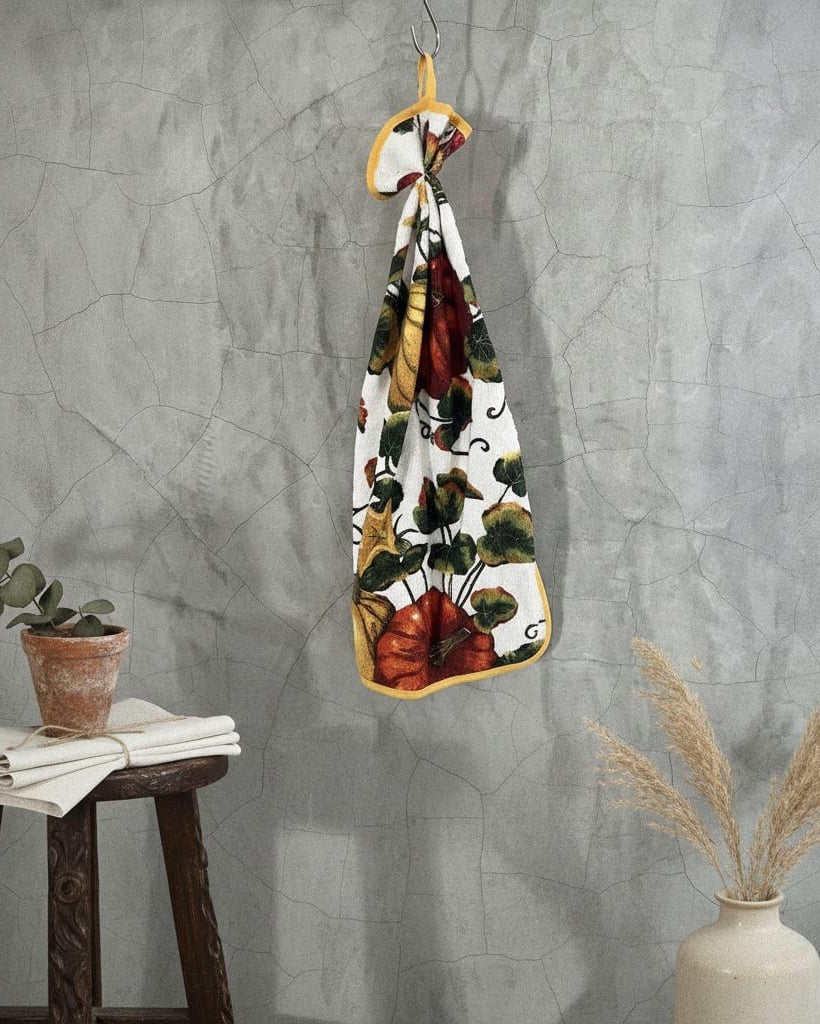 Decorative oven mitt with autumn design hanging on a gray textured wall.